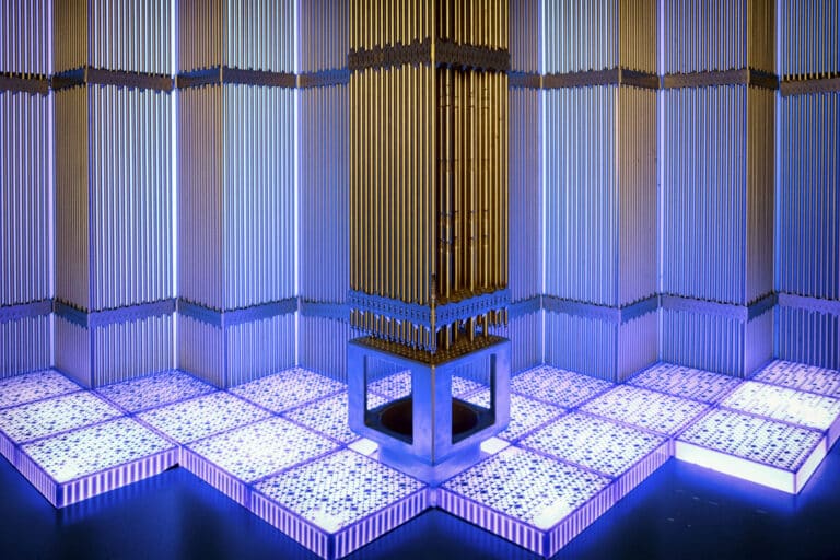 An installation featuring a tall, metallic column surrounded by illuminated panels with blue lighting.